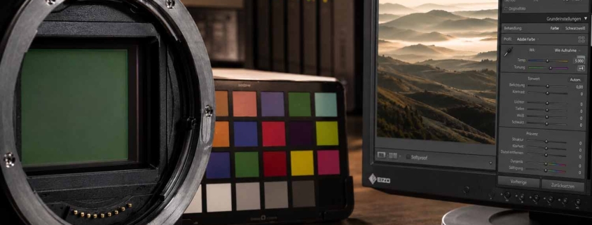 Nahaufnahme eines Kamerasensors, eines Farbkalibrierungsdiagramms und eines Computermonitors, auf dem die Bildbearbeitungssoftware Lightroom Workshop mit einem Landschaftsbild und einem Histogramm angezeigt wird.